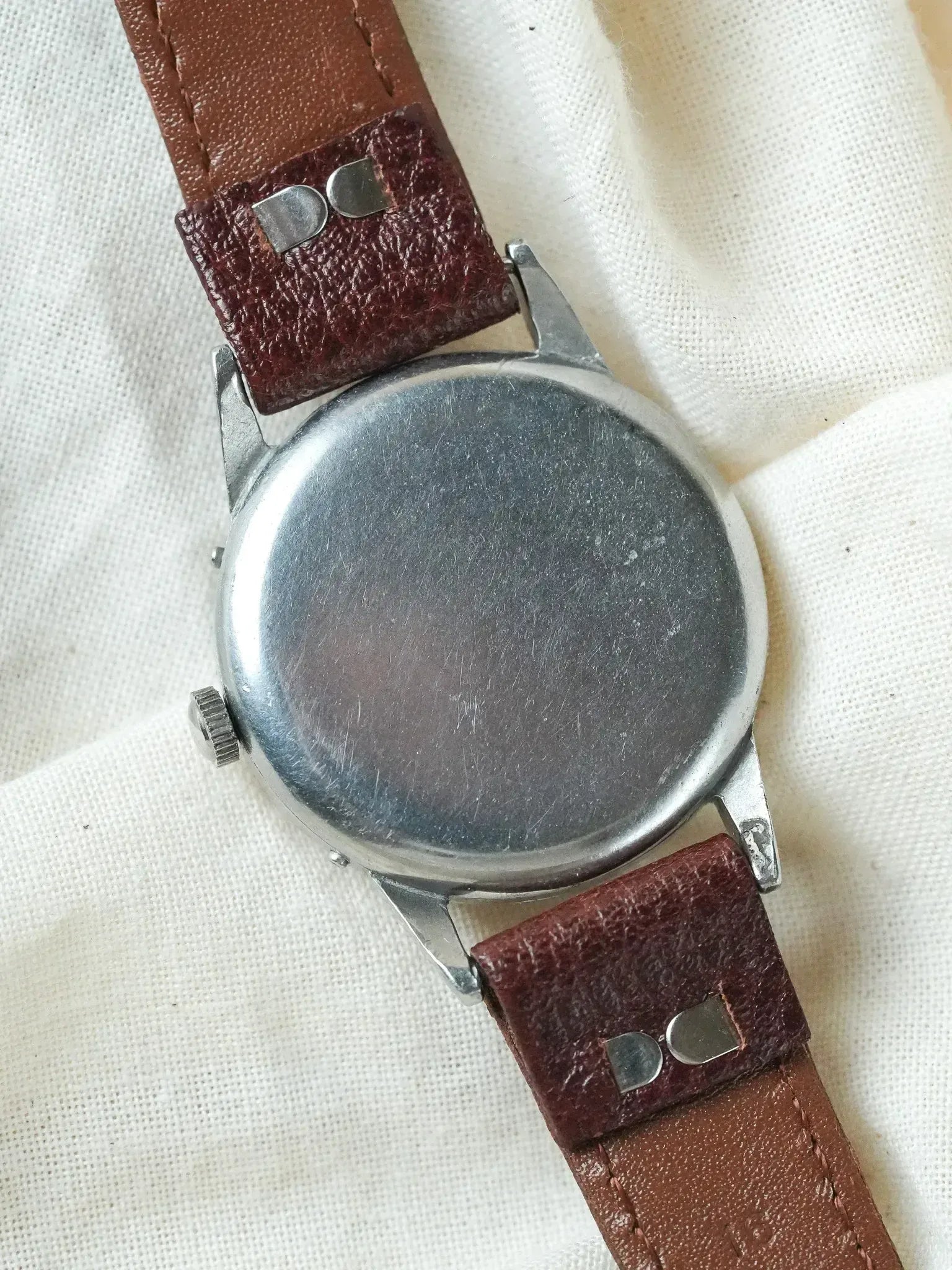 Vintage watch with stainless steel case and brown leather strap on fabric