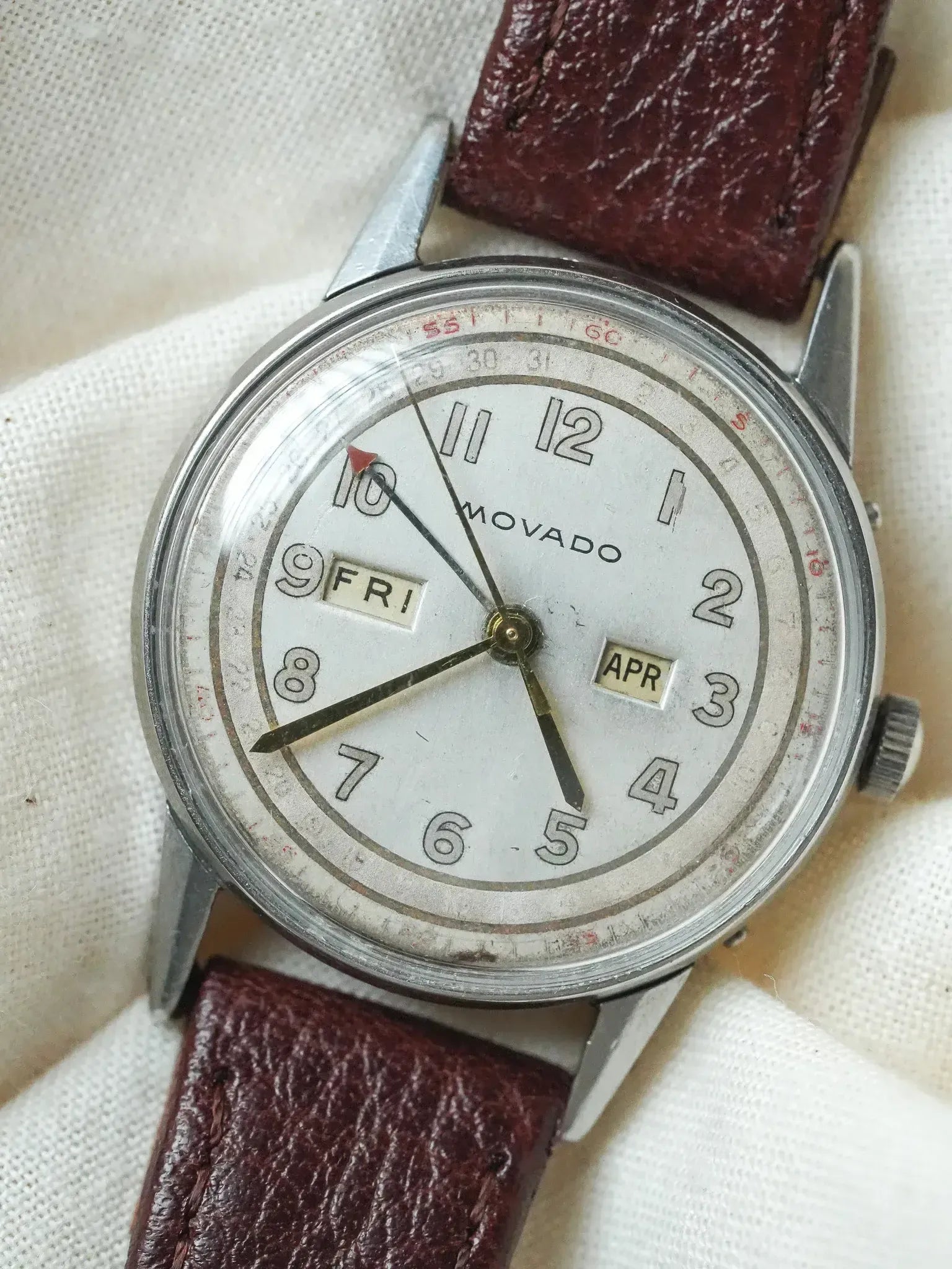 Vintage Movado watch with white dial, day-date windows, and brown leather strap