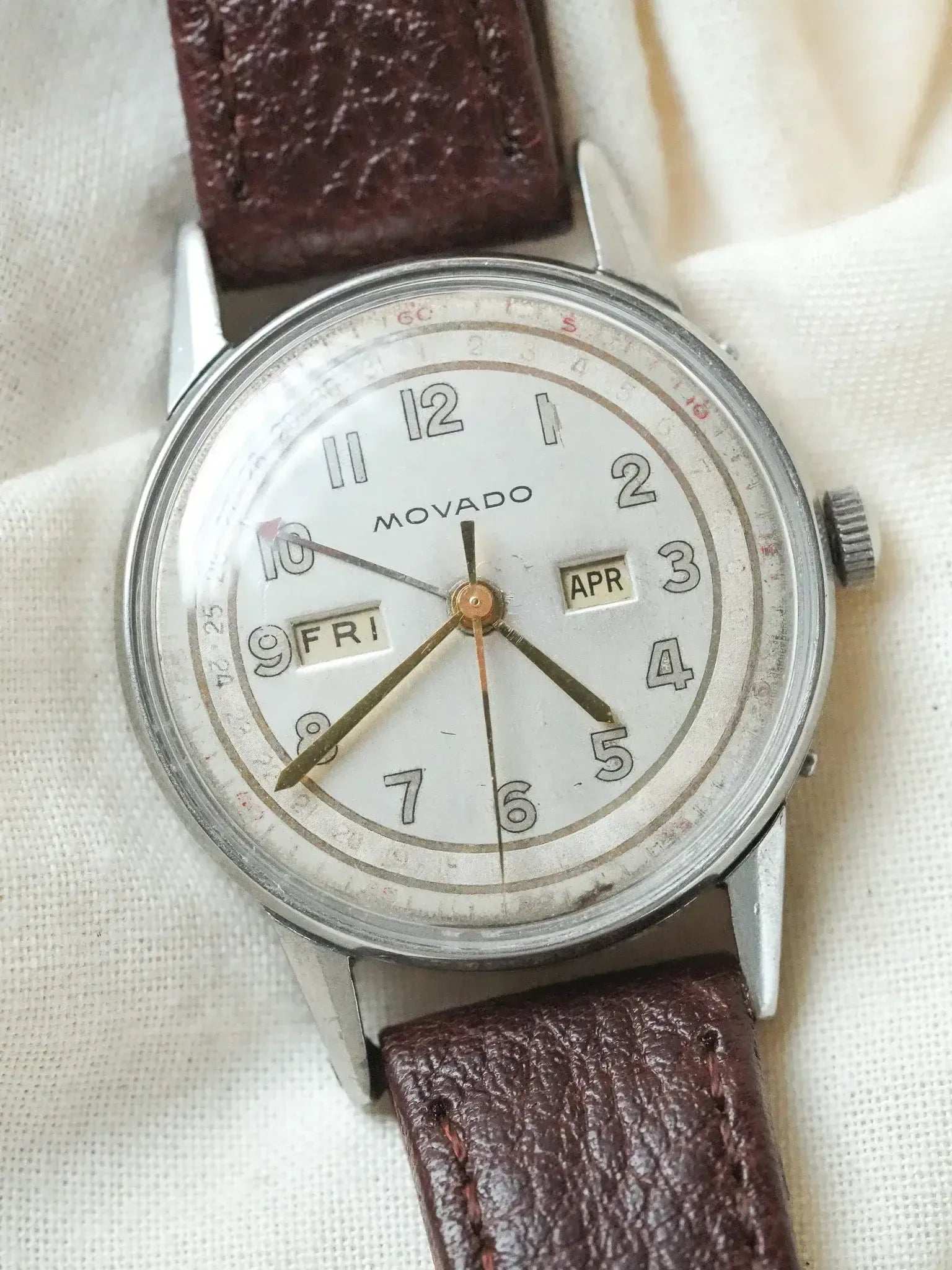 Vintage Movado watch with white dial, brown leather strap, day-date display