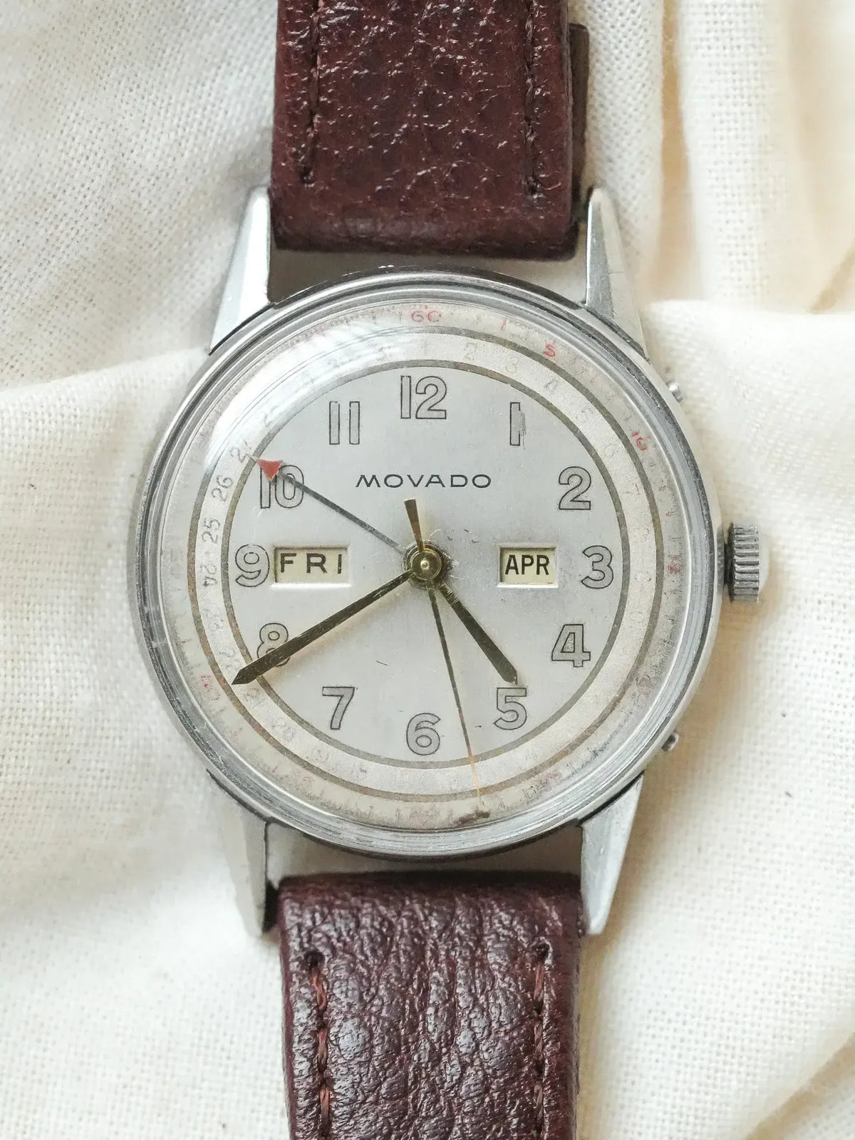 Vintage Movado watch with white dial, brown leather strap, day and date windows