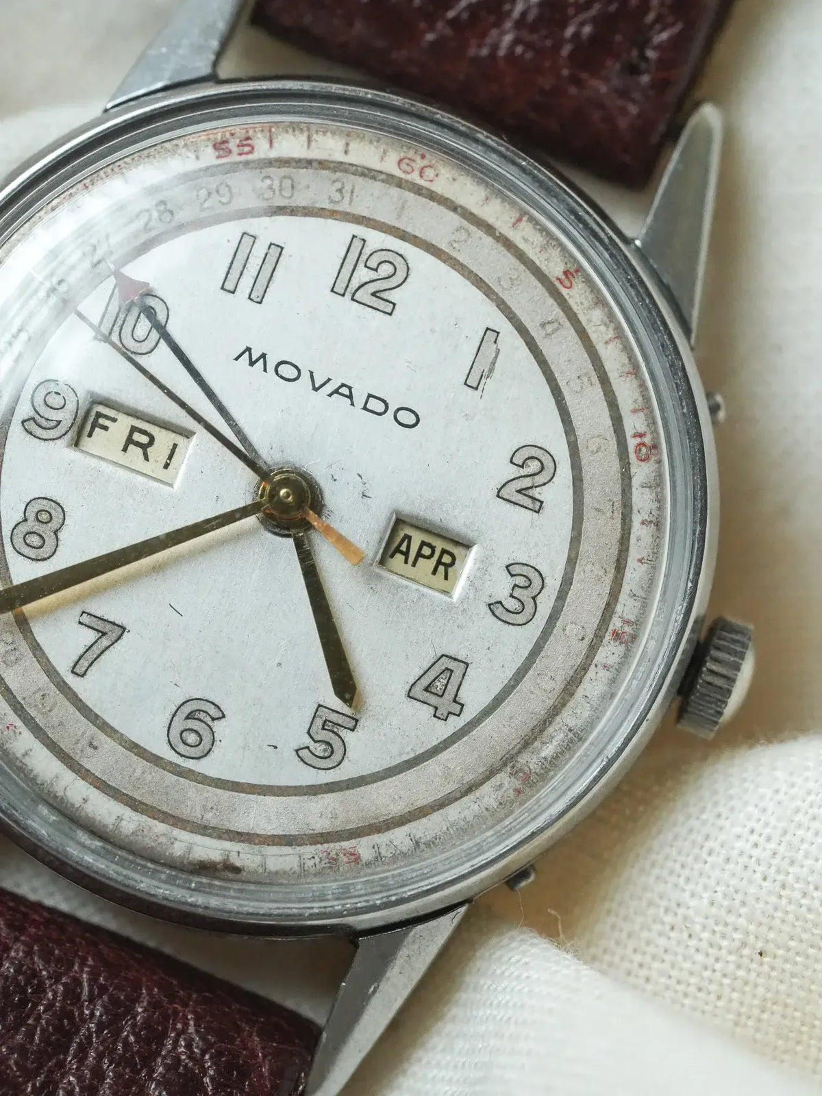 Vintage Movado watch with white dial, day-date windows, and brown leather strap