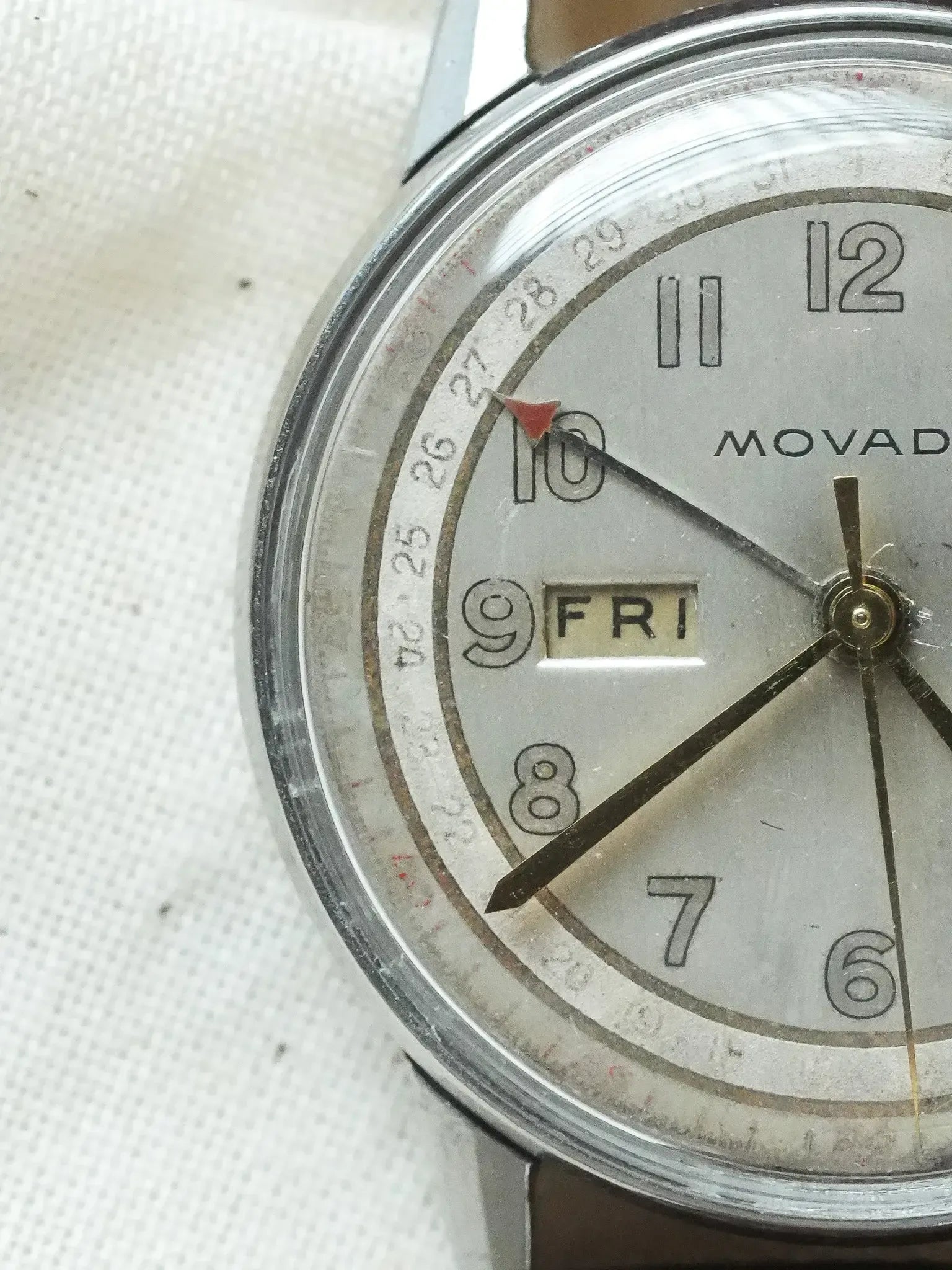 Vintage Movado watch with silver dial, day-date window, and brown leather strap