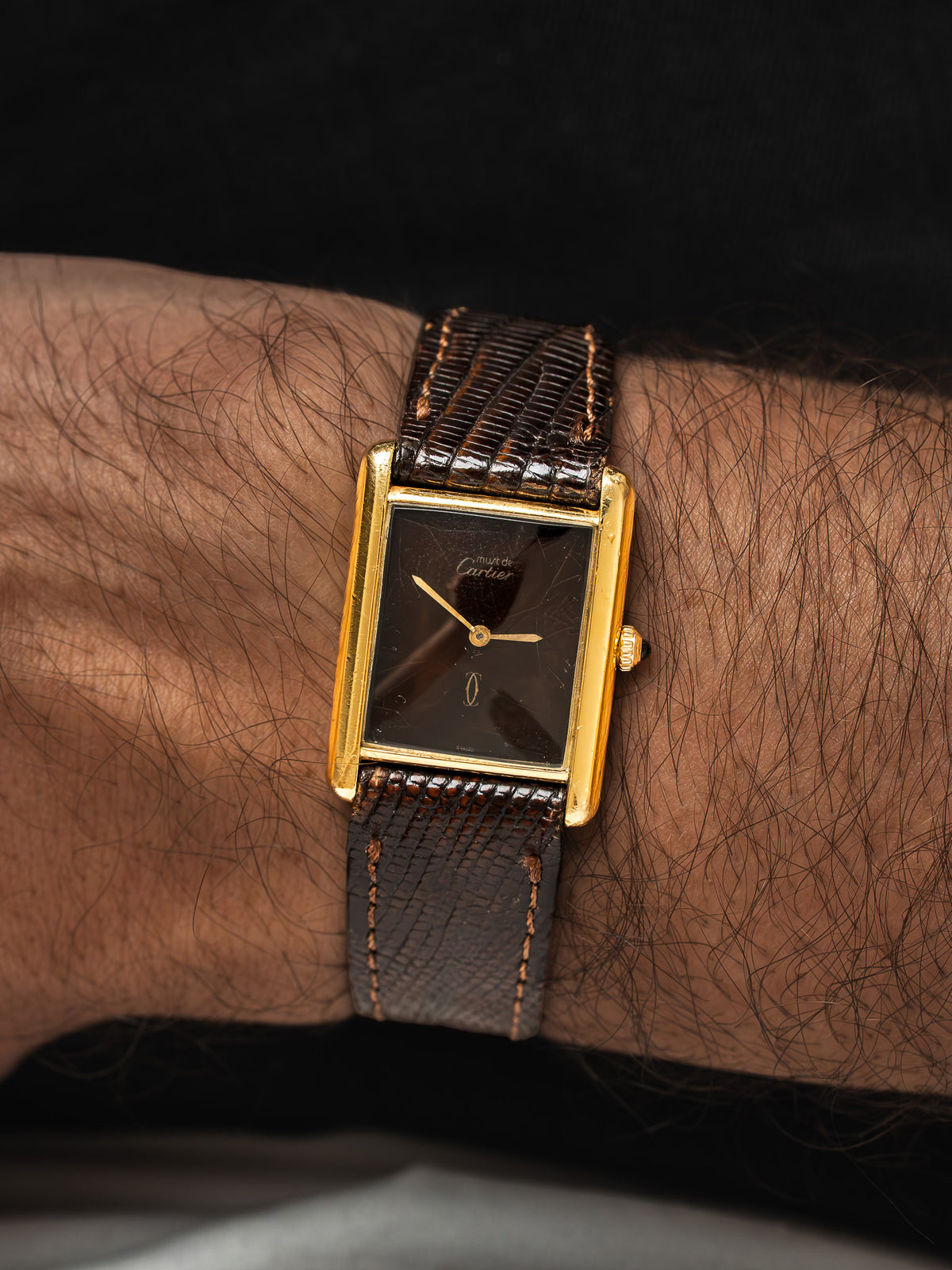 Montre Cartier vintage, boîtier rectangulaire doré, cadran noir et bracelet cuir marron