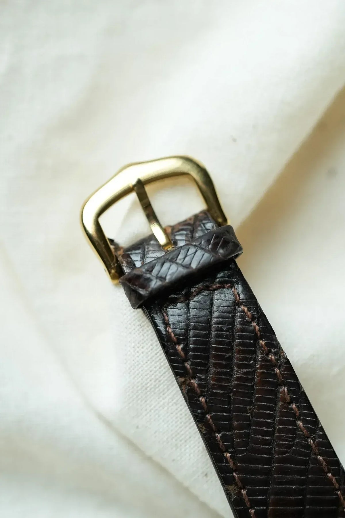 Vintage watch strap in dark brown lizard skin with gold buckle and tan stitching