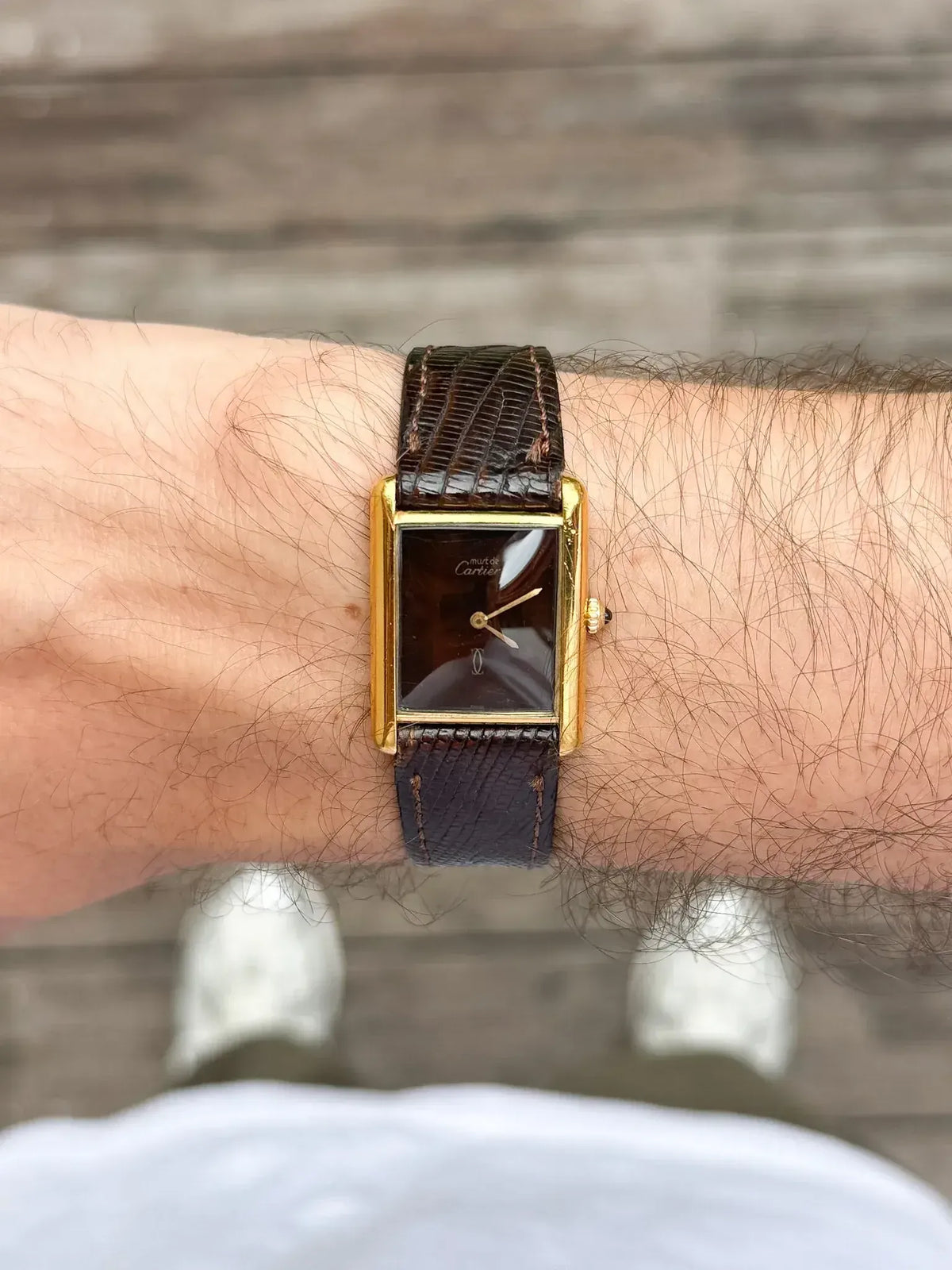Cartier Tank vintage watch with gold case, brown dial, and textured leather strap on wrist
