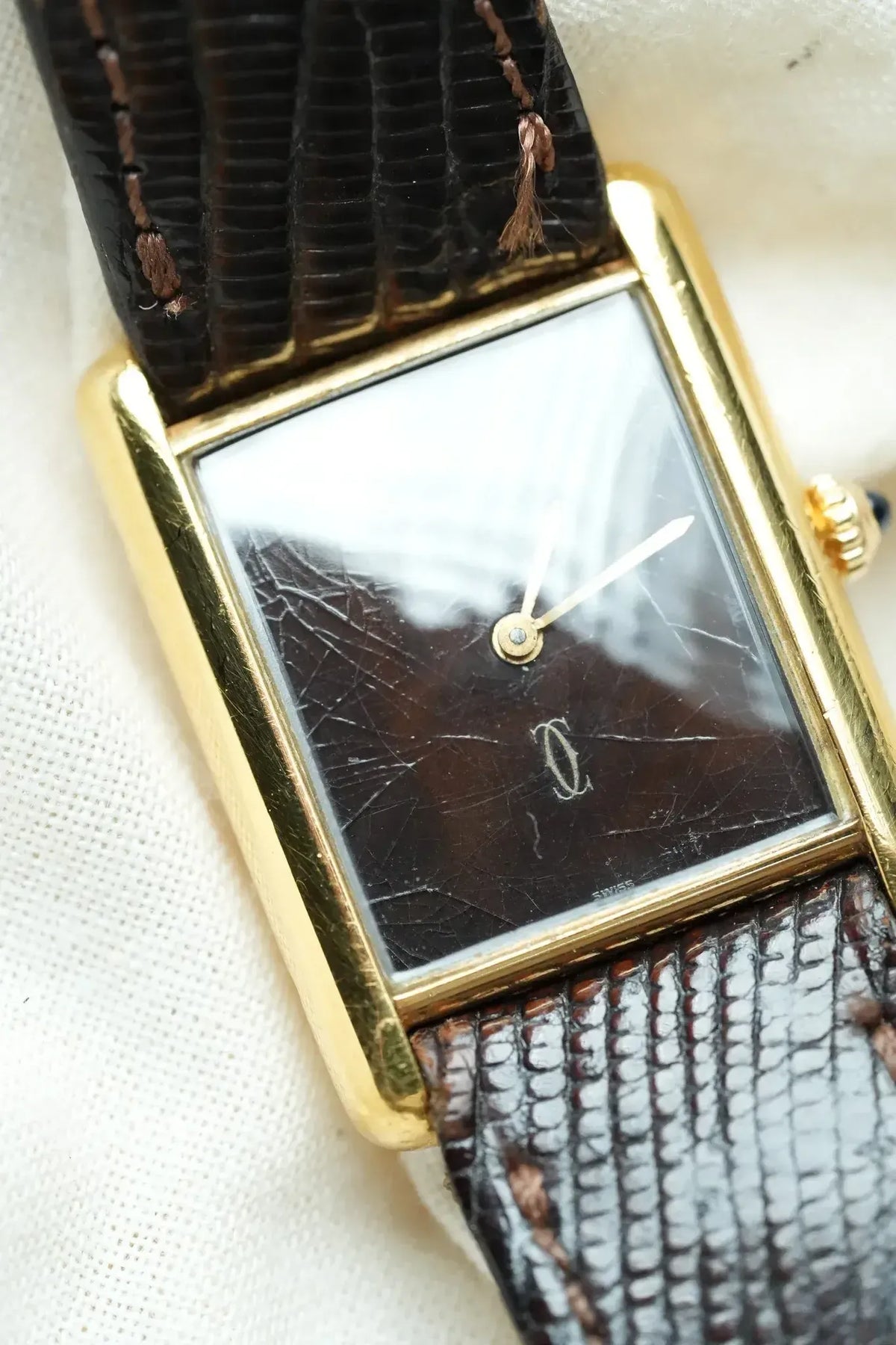 Cartier vintage watch with gold case, dark dial, and textured leather strap
