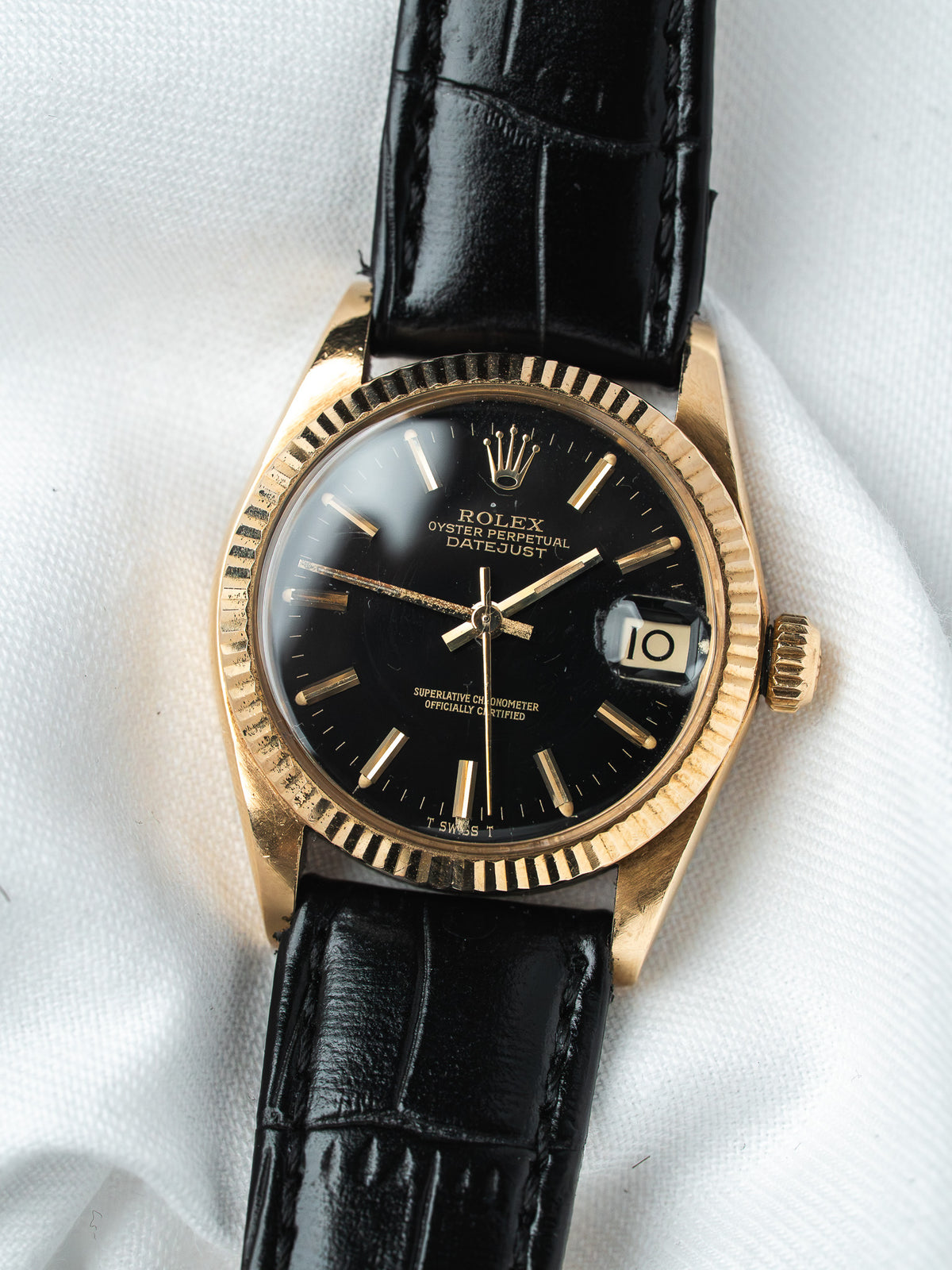Rolex Datejust vintage with black dial, gold bezel, and black leather strap