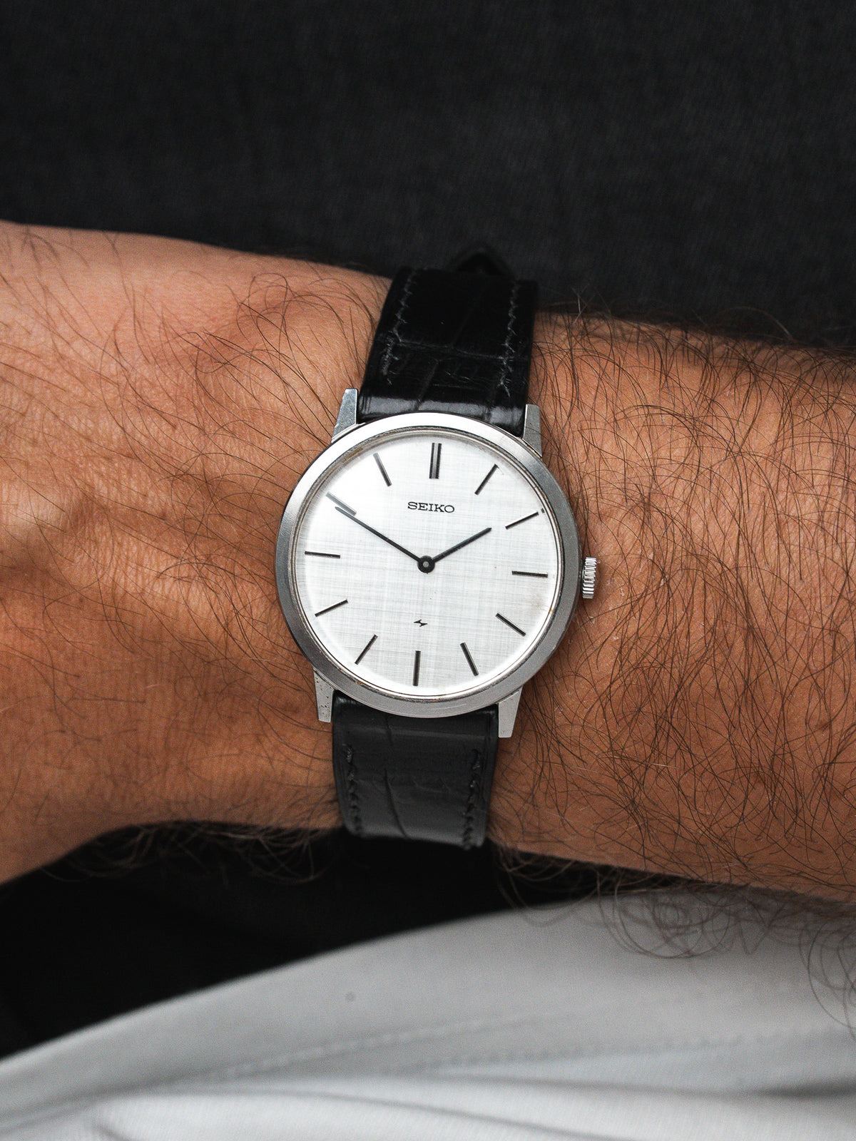 Seiko vintage watch with white dial, black leather strap, worn on wrist