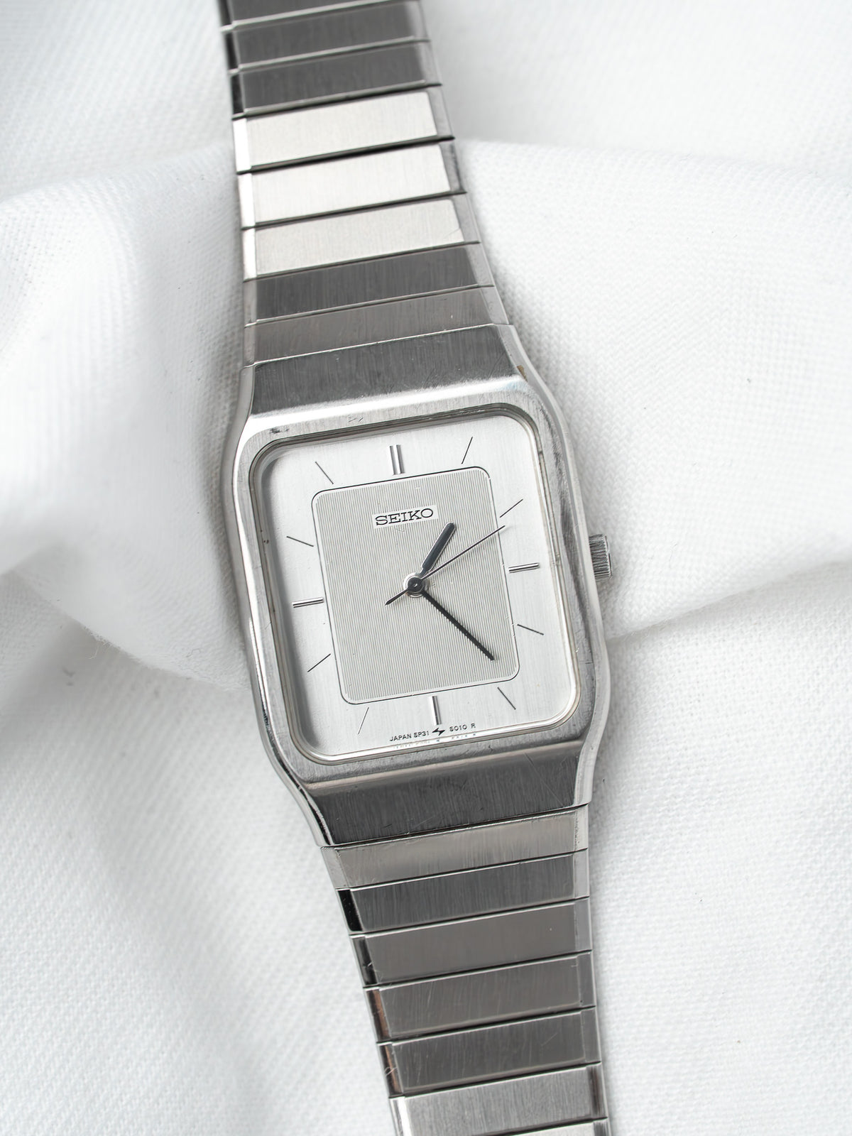 Seiko vintage watch with silver dial and metal bracelet on white fabric