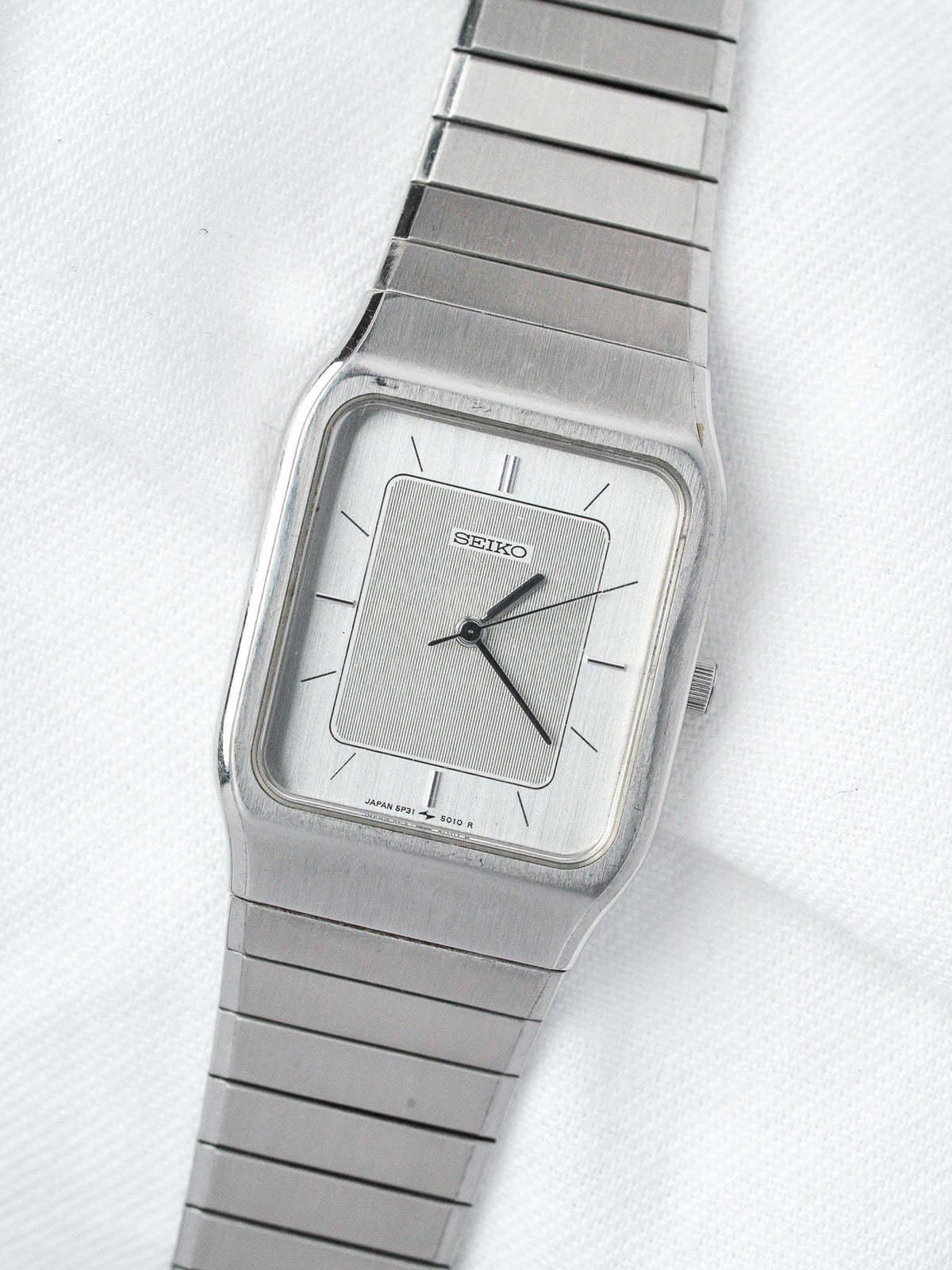 Seiko vintage watch with silver dial, rectangular case, and metal bracelet on white background
