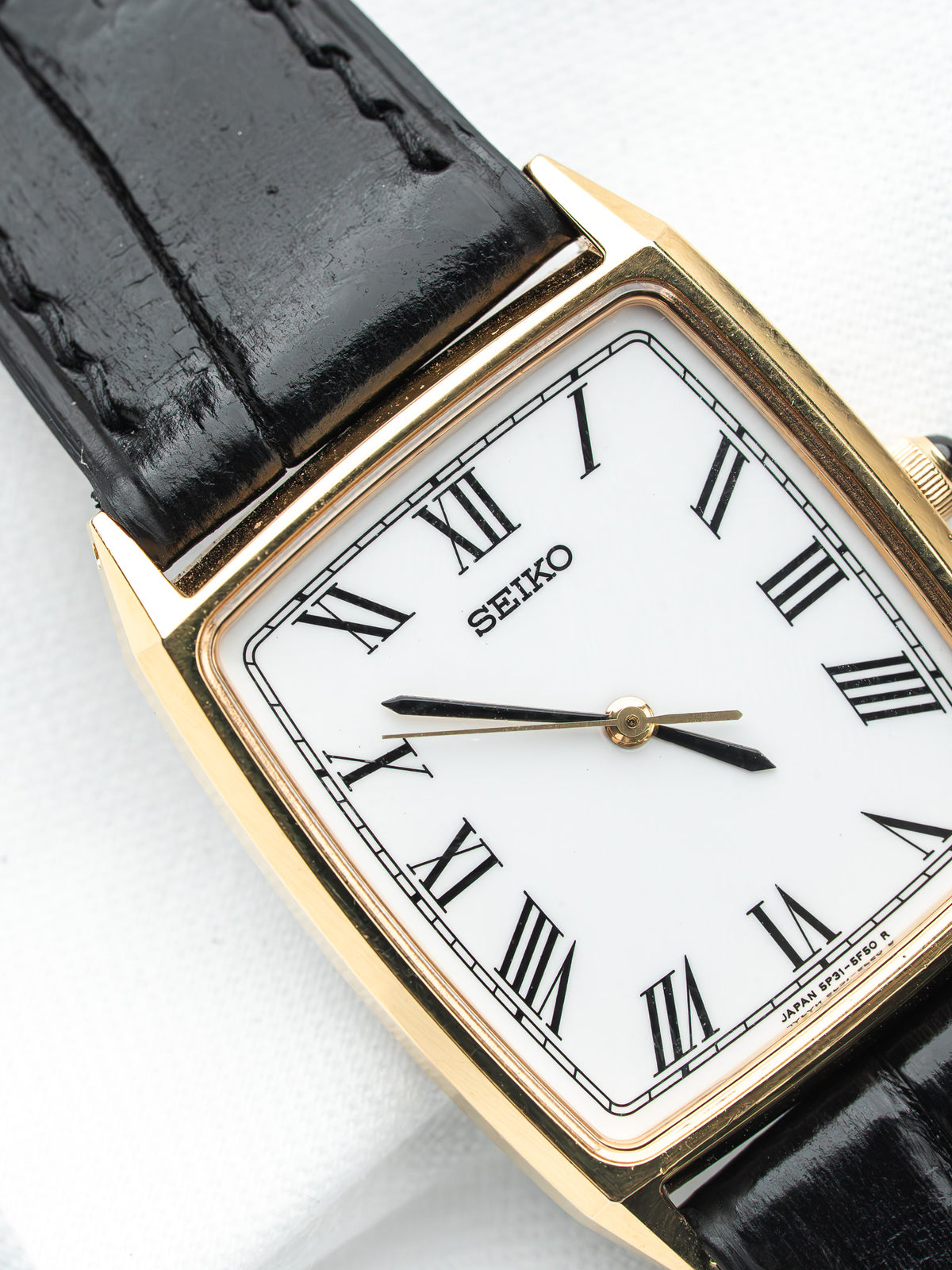 Seiko vintage watch with gold case, white dial, Roman numerals, black leather strap