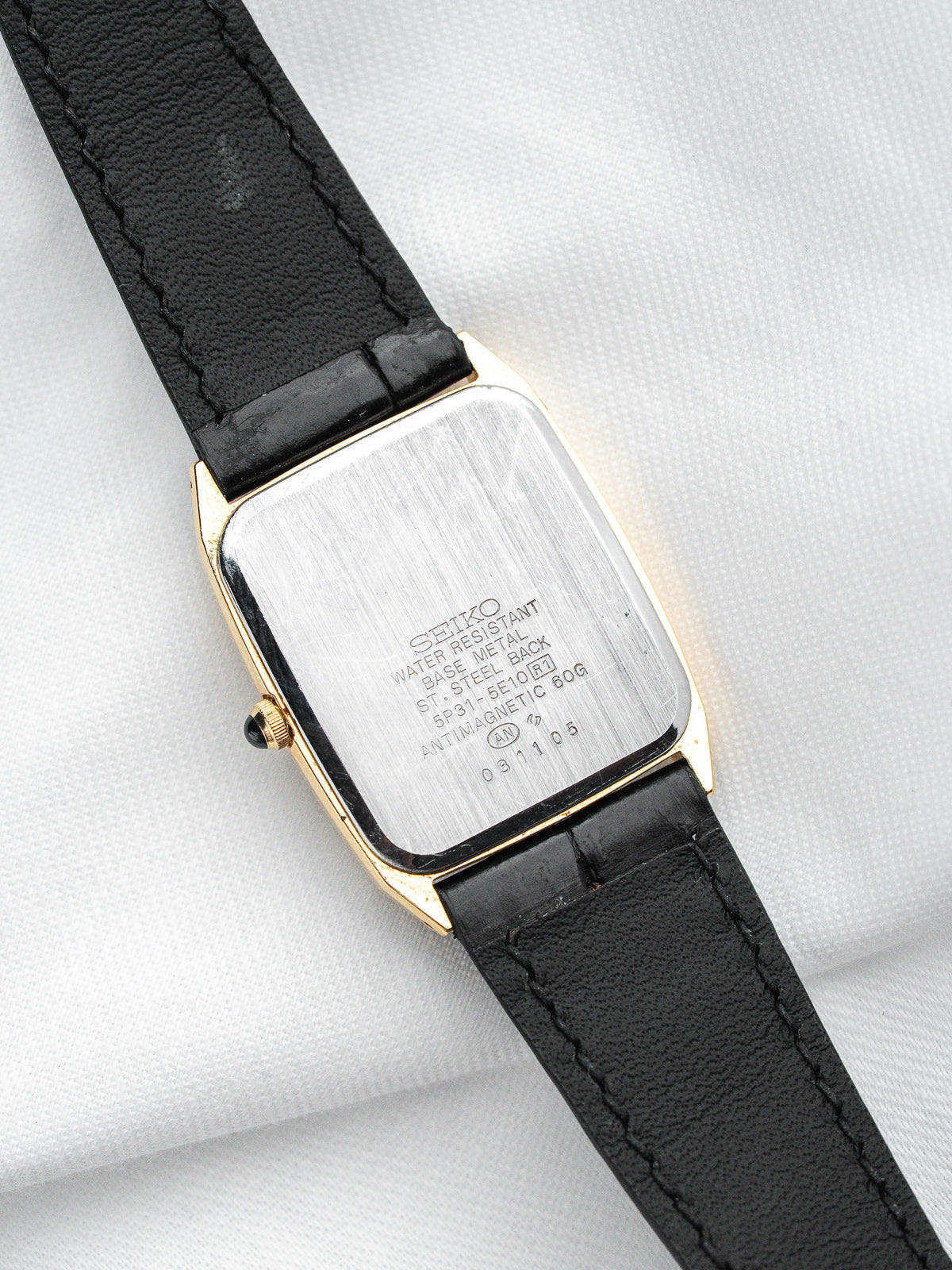 Seiko vintage watch with gold-tone case, black leather strap, steel back engraved details