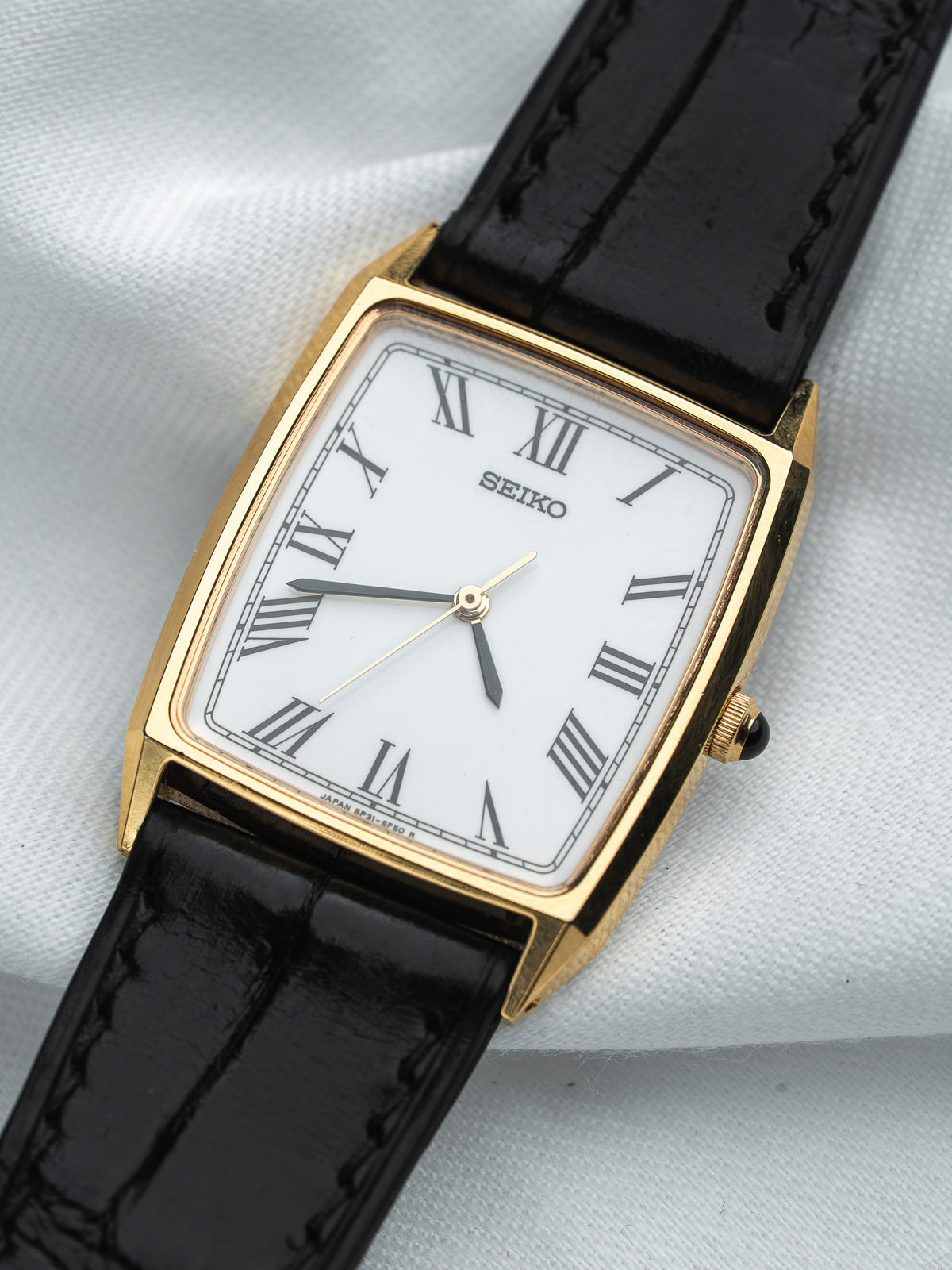 Seiko vintage watch with gold case, white dial, Roman numerals, black leather strap