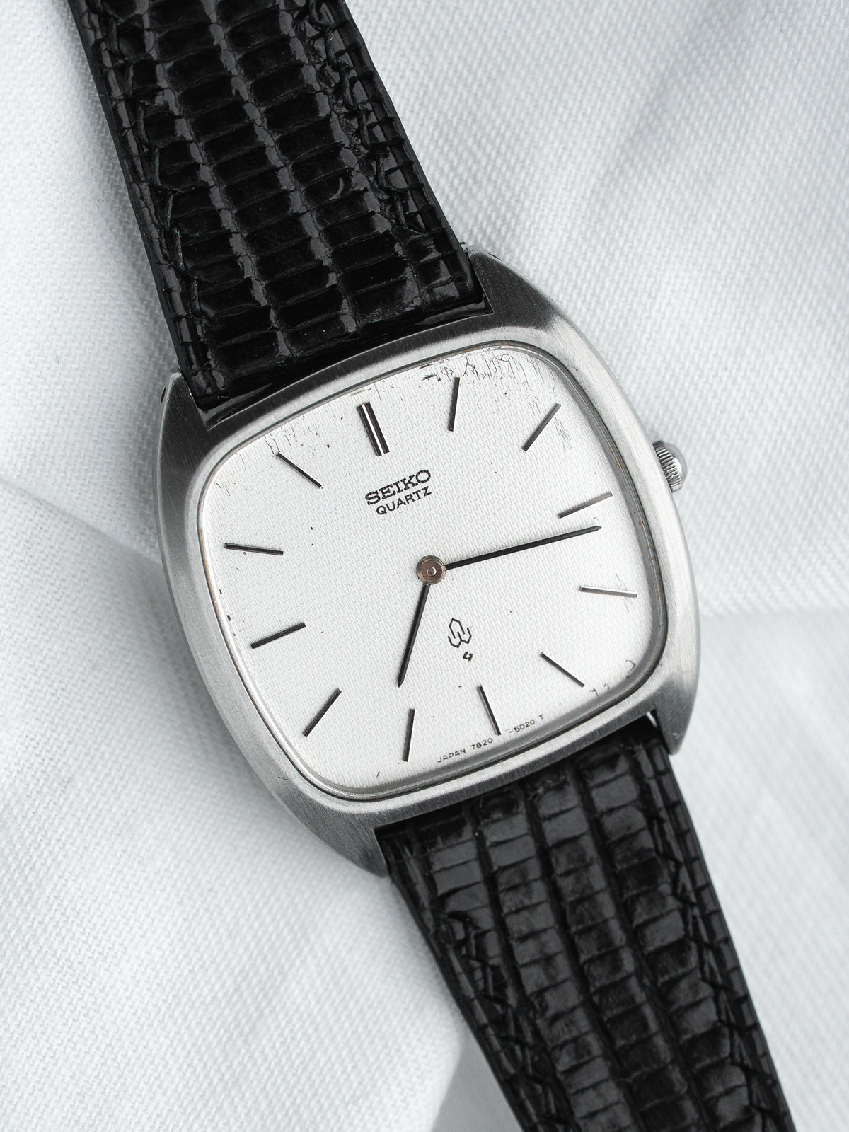 Seiko Quartz vintage watch with silver dial, black lizard strap, cushion case on white background