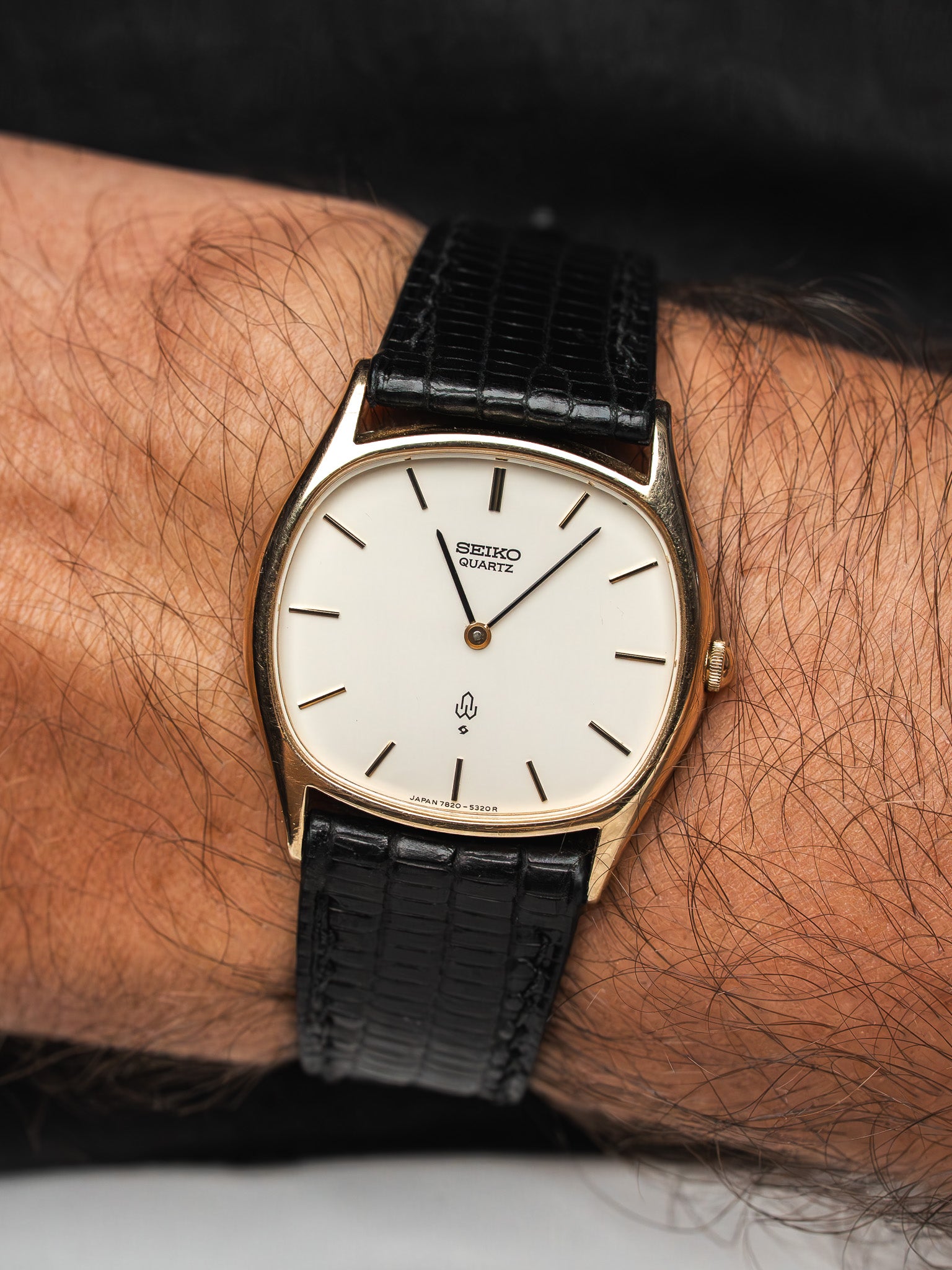 Vintage Seiko Quartz watch with gold case, white dial, black leather strap on wrist