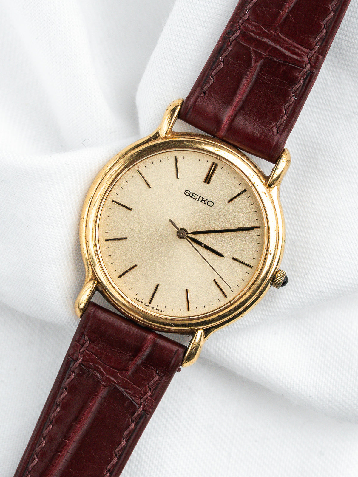 Seiko vintage watch with gold case, cream dial, and burgundy leather strap
