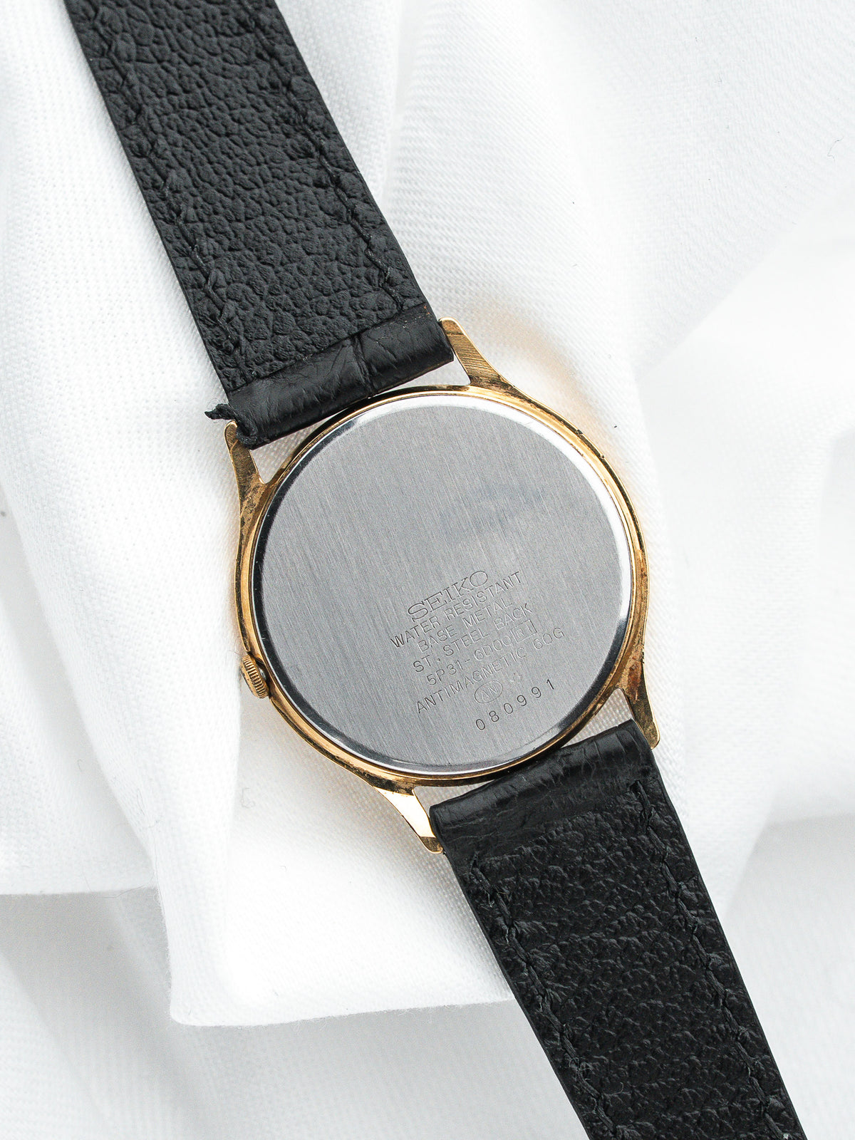 Dos d'une montre Seiko vintage avec boîtier plaqué or et bracelet cuir noir