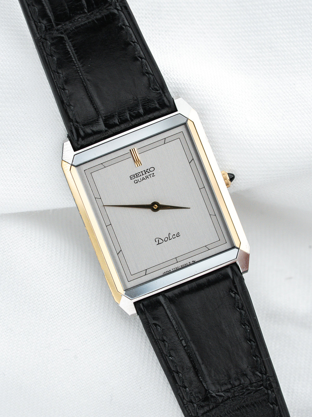 Seiko Dolce vintage quartz watch with silver dial, gold accents, black leather strap on white background