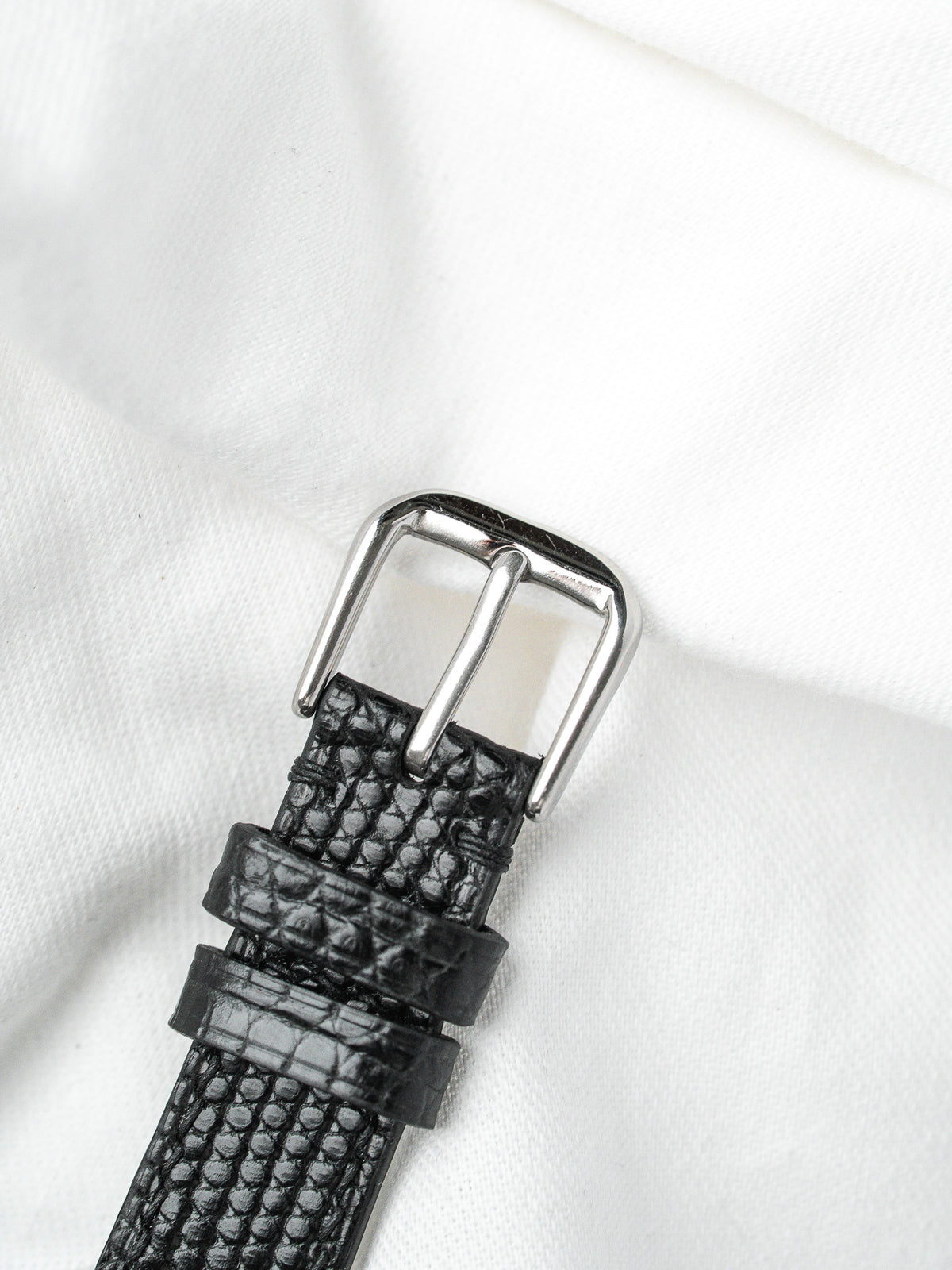 Bracelet de montre en cuir noir grainé avec boucle argentée sur fond blanc