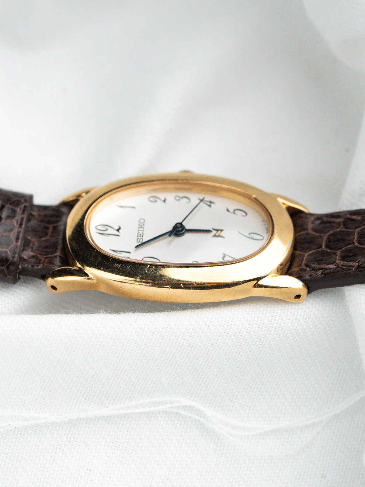 Seiko vintage watch with gold case, white dial, and brown leather strap