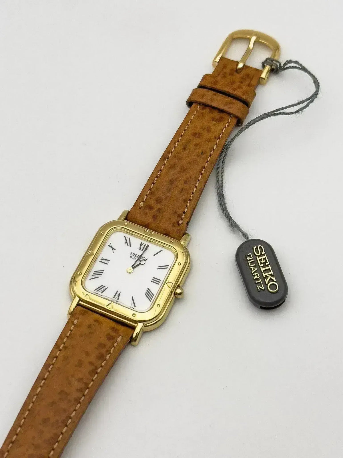 Seiko quartz watch with gold case, white dial, and brown leather strap