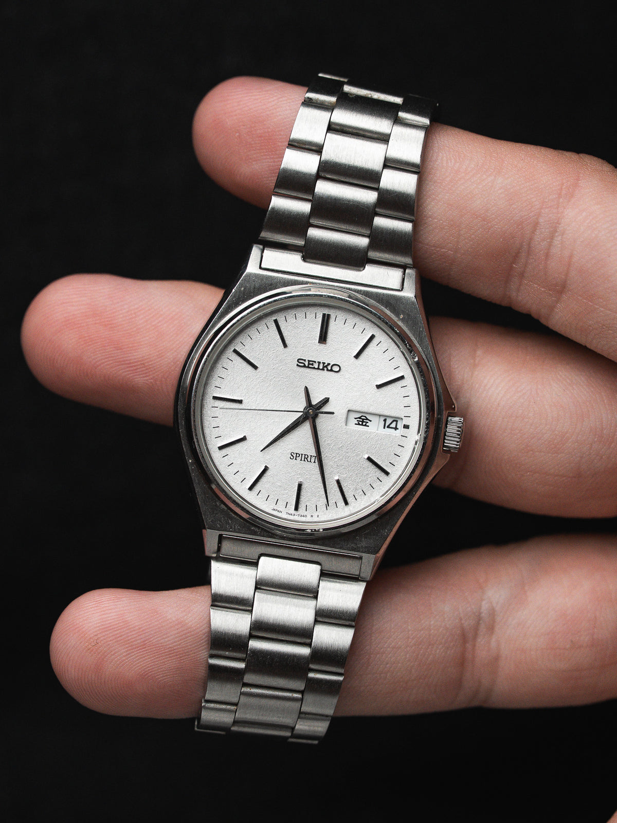 Montre Seiko Spirit vintage en acier, cadran blanc et bracelet métallique, portée au poignet