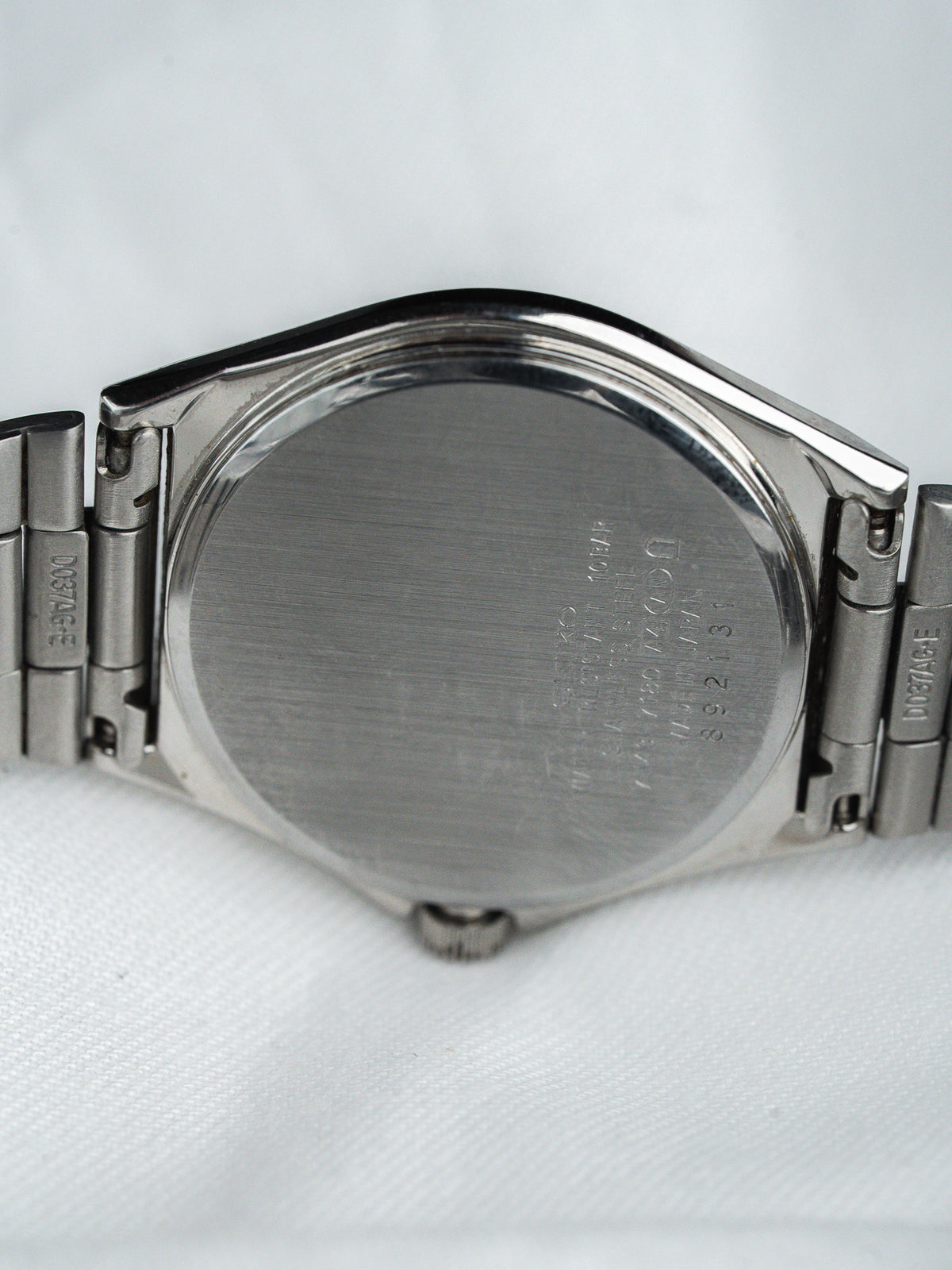 Seiko watch back case with engraved details, stainless steel bracelet on white background
