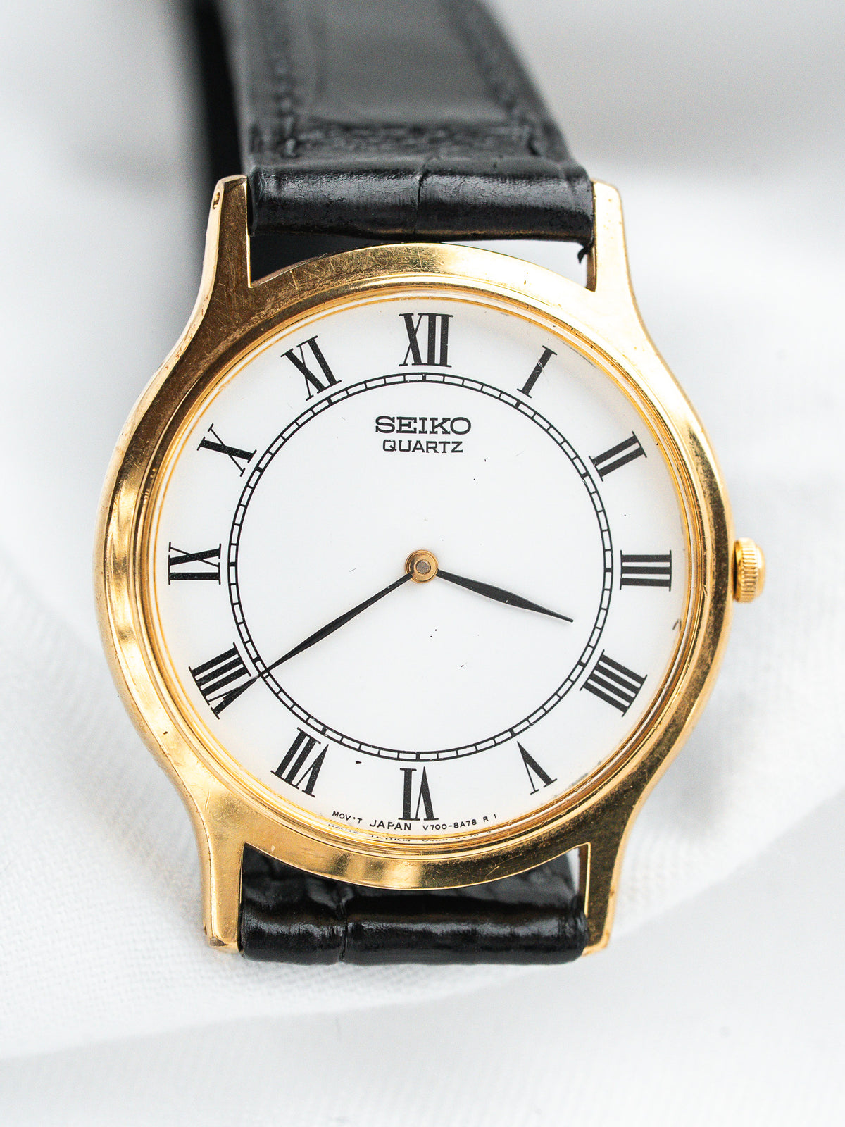 Seiko Quartz vintage watch with gold case, white dial, Roman numerals, black leather strap