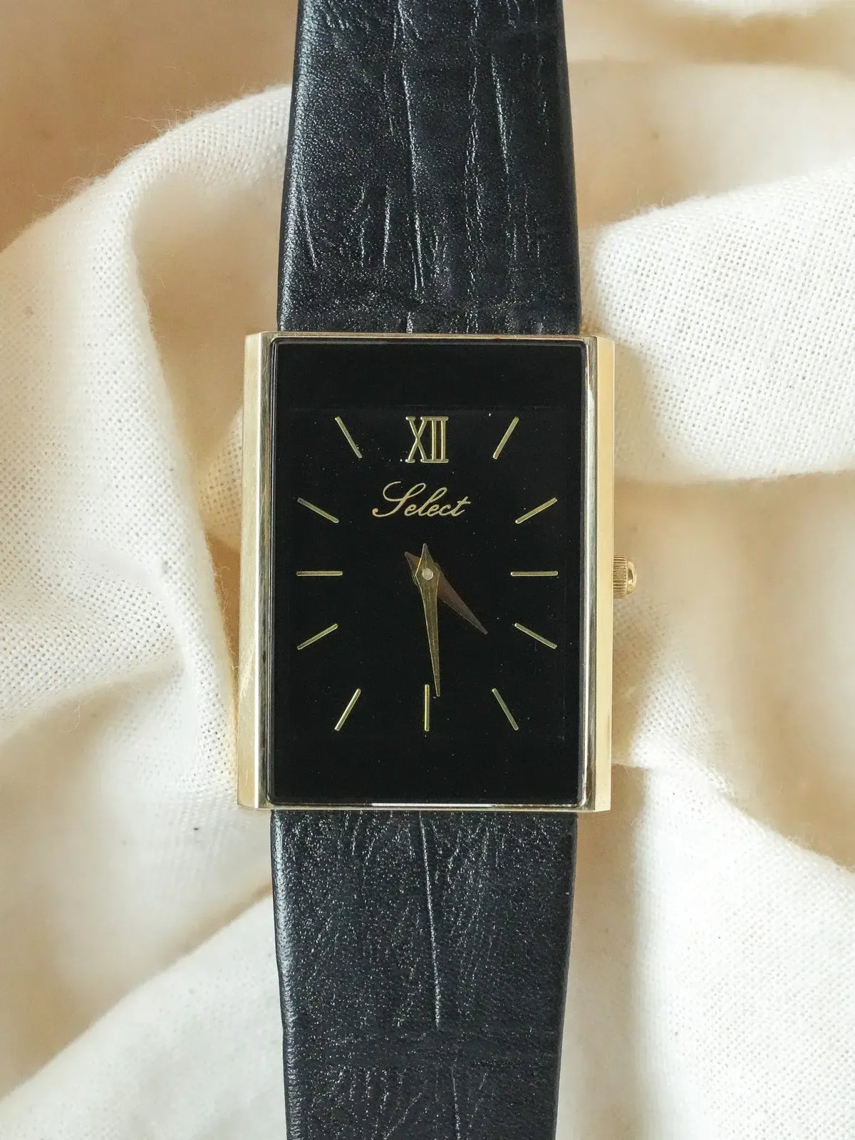 Select vintage watch with black dial, gold case, and black leather strap