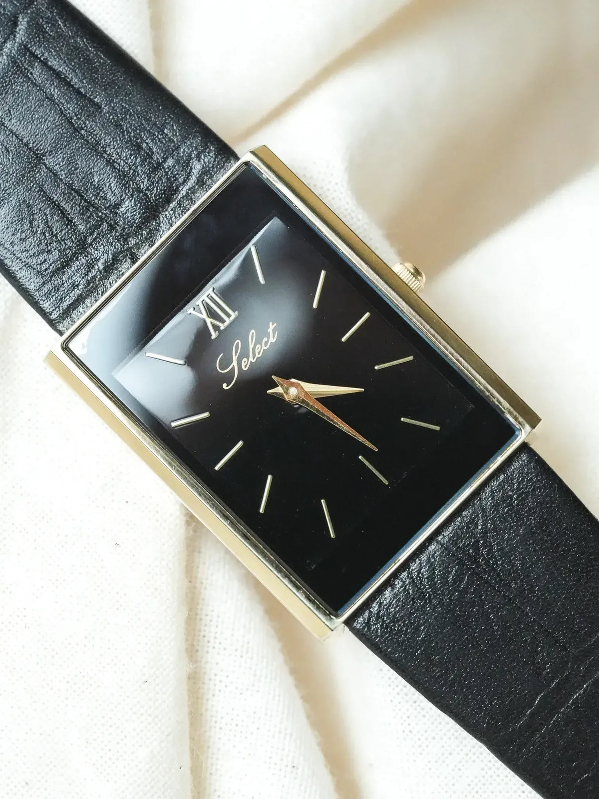 Select vintage watch with black dial, gold case, and black leather strap