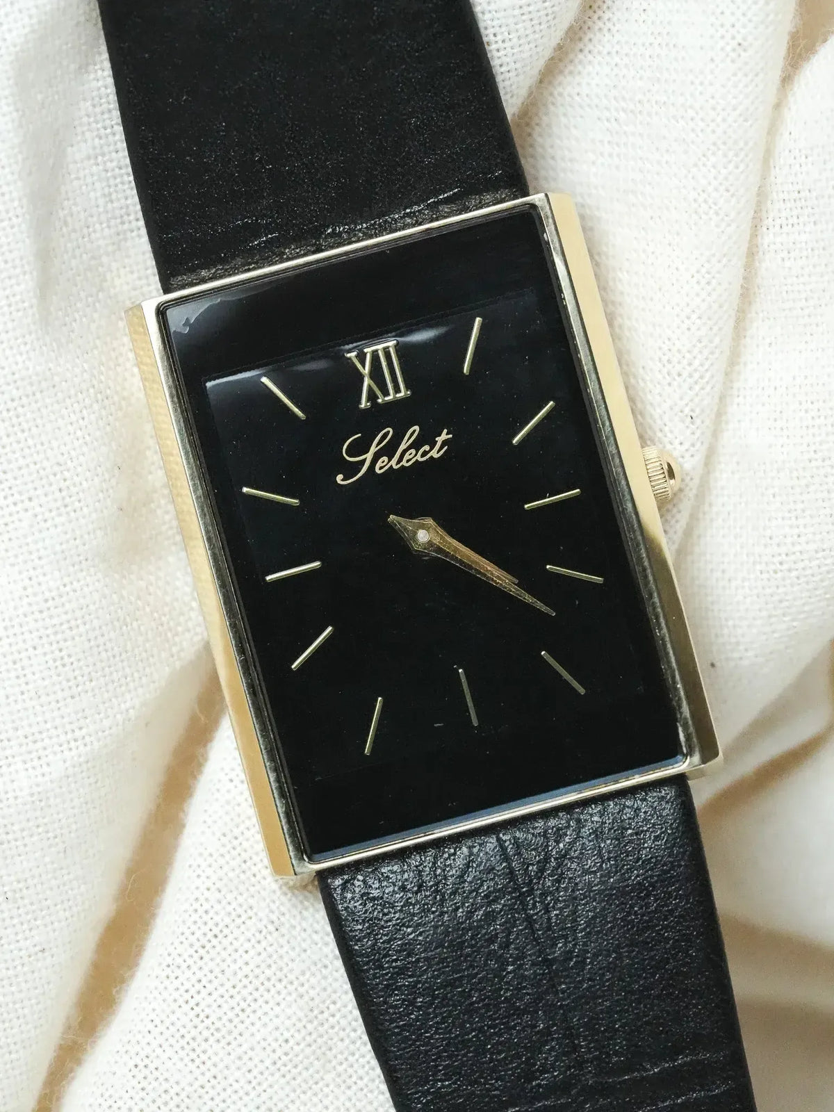 Select vintage watch with black dial, gold case, and black leather strap