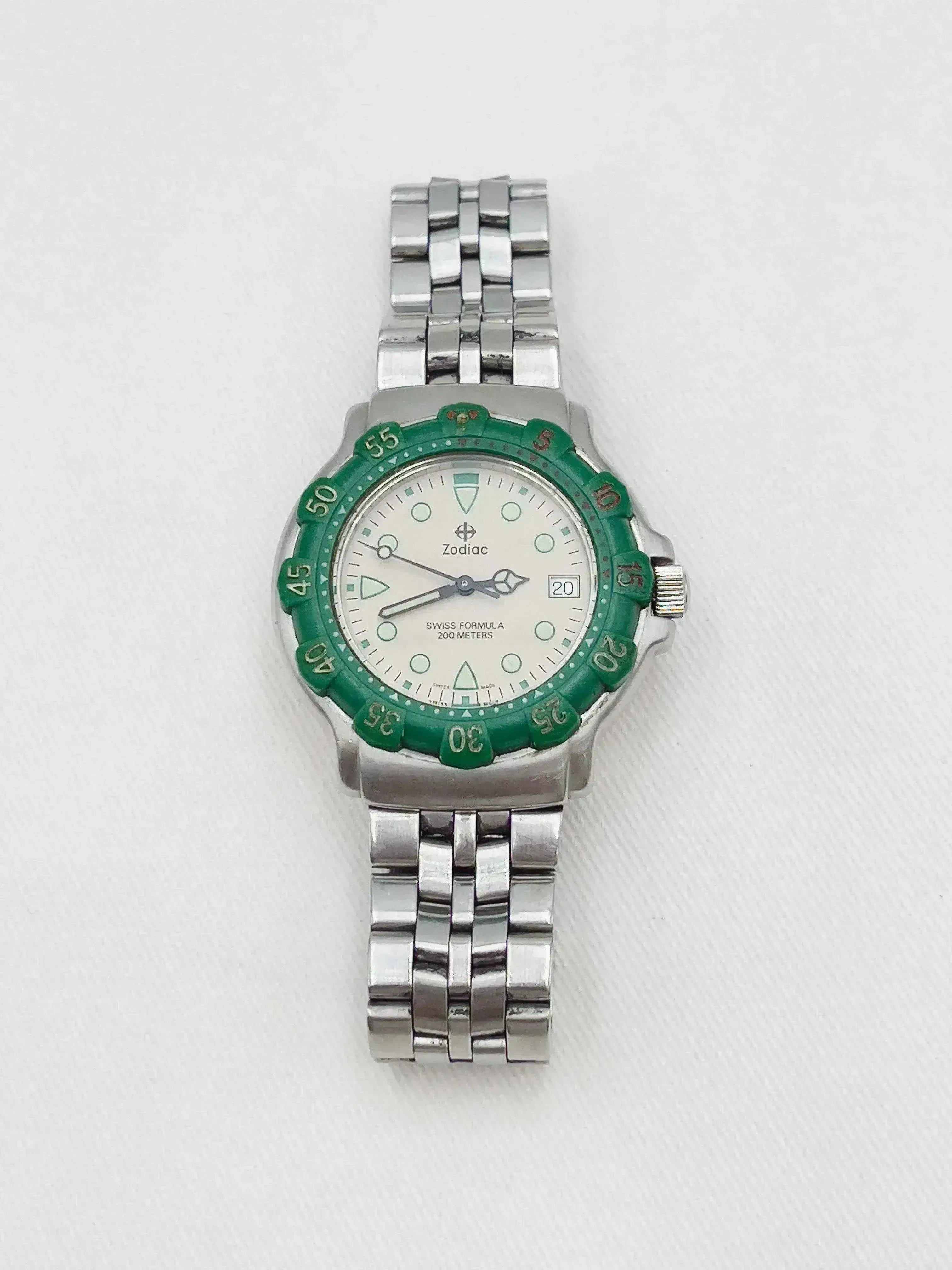 Zodiac vintage watch with green bezel, silver bracelet, white dial on neutral background